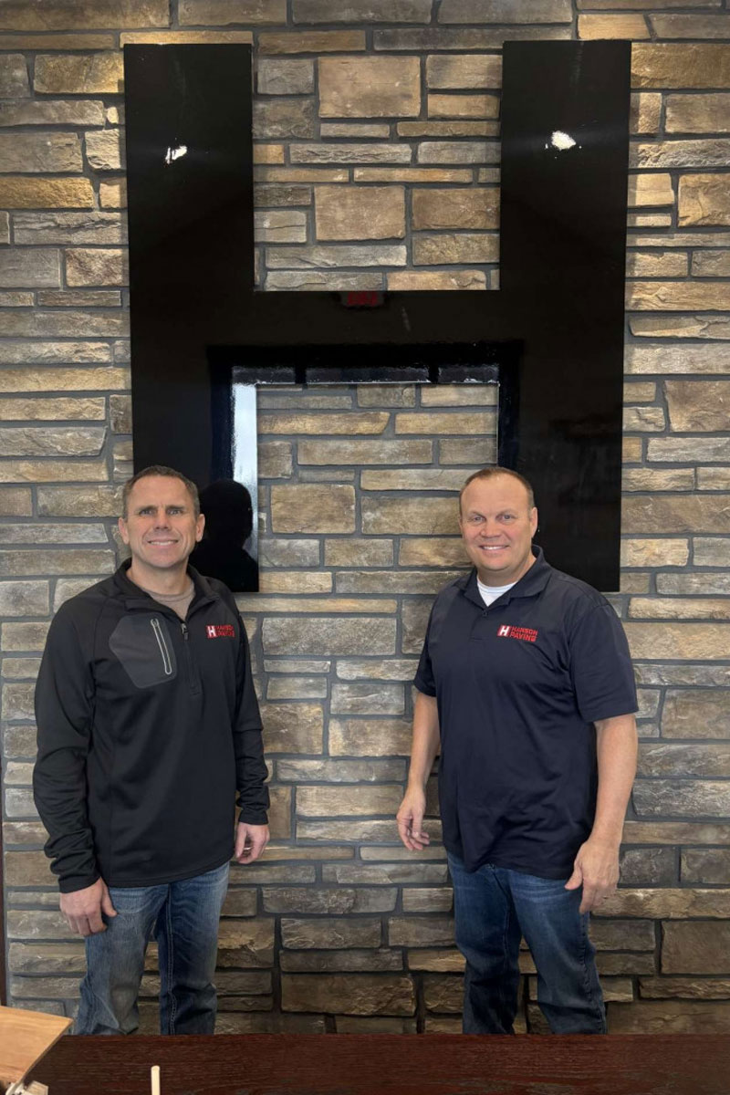 Two men standing next to logo on wall